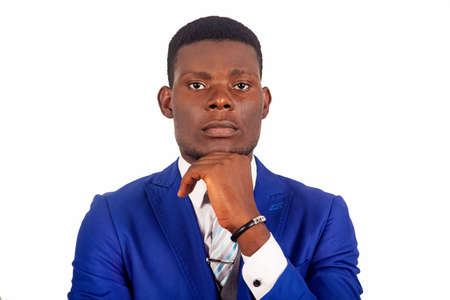 Serious young businessman wearing a blue jacket touching the chin while looking at the cameraの写真素材