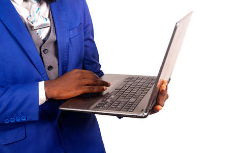 a handsome young businessman in suit standing isolated on white background working using a laptopの写真素材