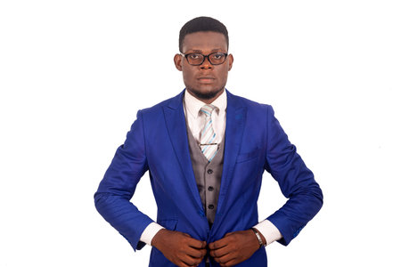 a handsome businessman standing isolated on white background adjusting his jacketの写真素材