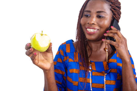 beautiful adult businesswoman talking on mobile phone and holding a fresh apple smilingの写真素材