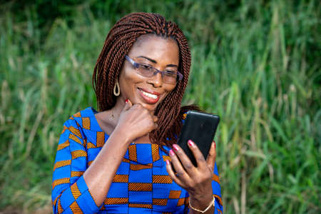 a beautiful mature woman in traditional dress standing in a park looking at mobile phone smiling.の写真素材