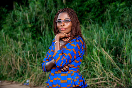 a beautiful mature woman in traditional dress standing in a park looking at the camera in profile smiling.の写真素材