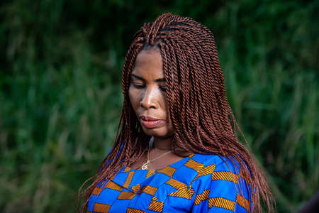 beautiful adult business woman with braided hair standing sadly in the park.の写真素材