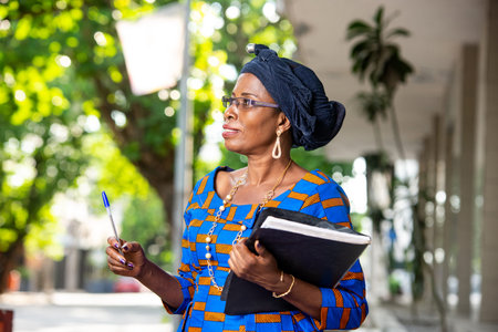 beautiful adult businesswoman standing sideways and holding a folder with a pen in hand on the...