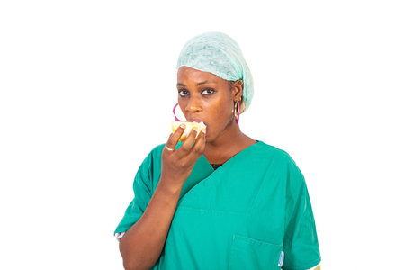 Beautiful young woman doctor in uniform drinking orange at the hospital and looking at the camera.