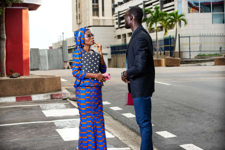 businessman and businesswoman standing on the street, talking about business with each one a notebook in hand.の写真素材