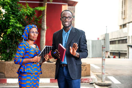 businessman and businesswoman each holding a notebook and discussing business on the street.の写真素材
