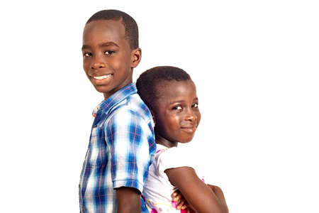 boy and girl standing back to back looking at camera smiling.の写真素材