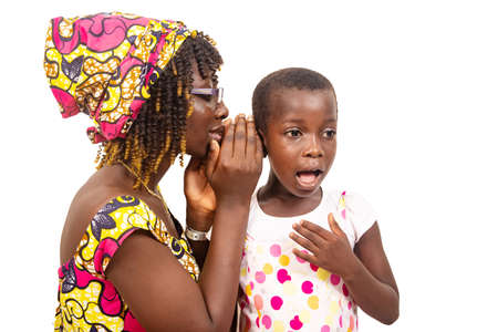 young woman whispering to her daughter.の写真素材
