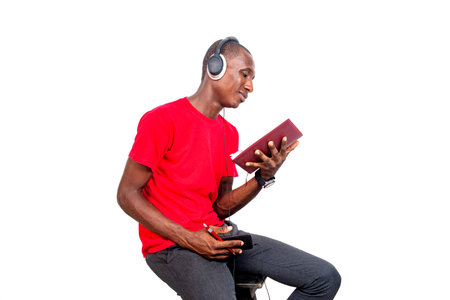 handsome adult man listening to music with headphones and reading a book.