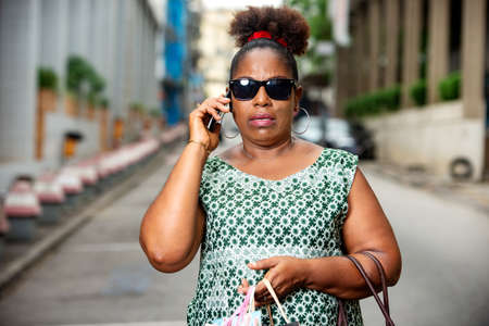 mature business woman wearing black glasses talking on mobile phone on the street.の写真素材