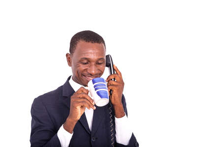 happy adult businessman talking on a mobile phone and drinking a cup of coffee in hand.の写真素材