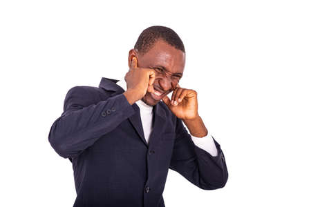 a handsome businessman in jacket standing on white background with fingers on his ears looks at the camera laughing.の写真素材
