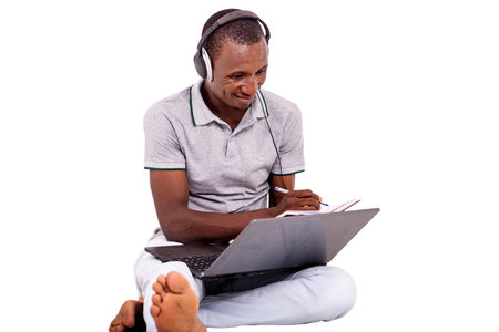a handsome student in a t-shirt sitting on the ground isolated on a white background communicating...