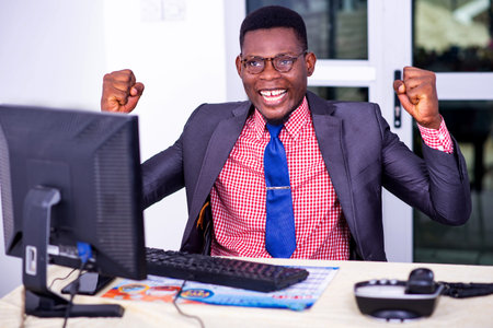 adult businessman looking at laptop screen in office and making a winning gesture.