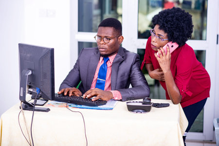 businessman and businesswoman working together on laptop in the office. woman talking on cellphone.