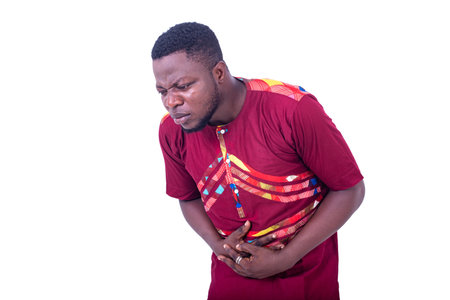 handsome young man suffering from stomach ache and keeping hands on stomach.