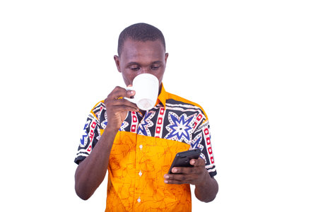 handsome young man drinking a cup of coffee and holding a mobile phone.