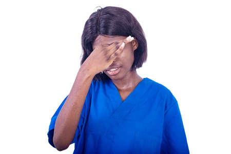 young female nurse in uniform standing on white background with stethoscope feeling pain in eyes.の写真素材