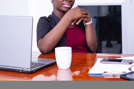 young businesswoman sitting at desk with laptop thinkingの写真素材