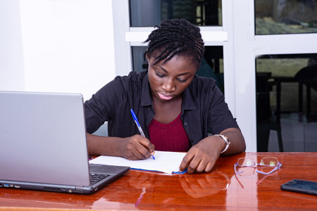 beautiful young businesswoman sitting at busy desk writing on clipboard.の写真素材