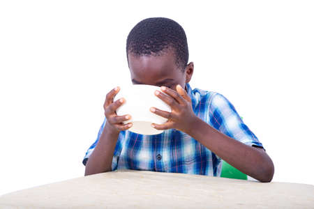 handsome little child boy sitting at table and drinking yogurt at home.の写真素材