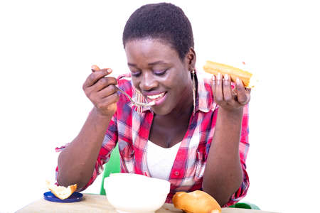 beautiful young woman sitting at the table having breakfast while eating a piece of bread and drinking coffee.の写真素材