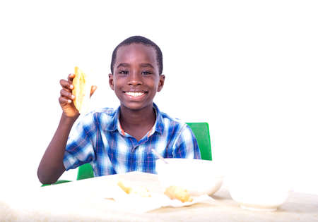 cute little boy sitting at table holding a piece, smiling at camera.の写真素材