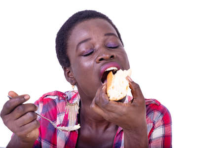 beautiful young woman sitting at the table eating a piece of bread with her eyes closed.の写真素材