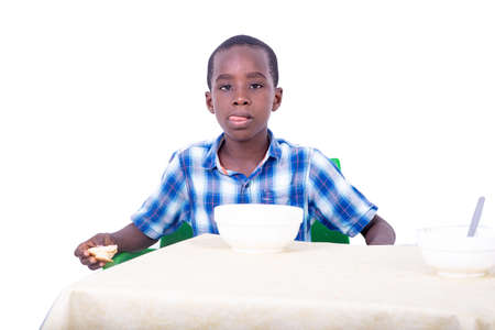 handsome little boy sitting at the table having breakfast while drinking milk at home.の写真素材