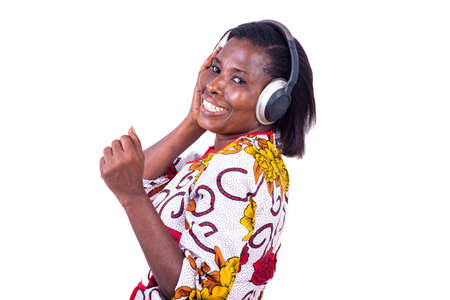 a woman in a corsage standing on a white background making dance moves to the rhythm of the music while listening using headphones while smilingの写真素材