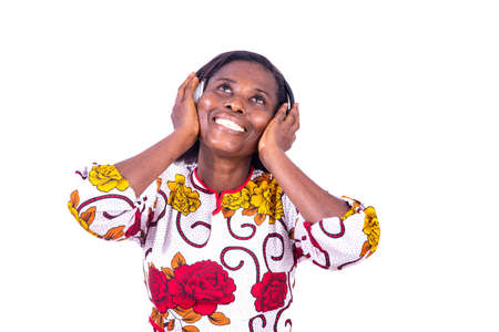 a woman in a corsage standing on a white background listening to music using headphones looking up laughingの写真素材