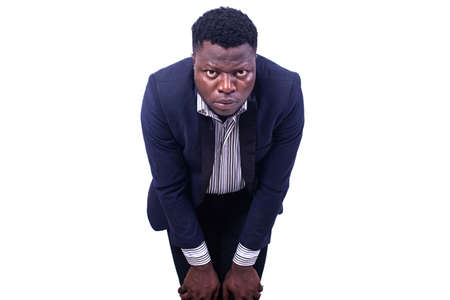 young tired businessman keeping hands on knees while looking at camera.の写真素材