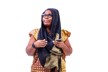mature woman wearing glasses, standing with cellphone in hand and looking up.