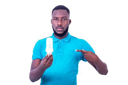 handsome serious young man wearing a blue t-shirt, pointing a finger at a light bulb while looking...
