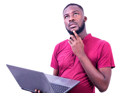 young businessman wearing red t-shirt standing on white background working with laptop while...