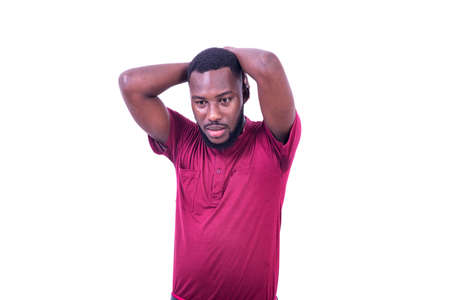 a young man in a t-shirt standing on a white background with his hands on his head looking unhappy.の写真素材