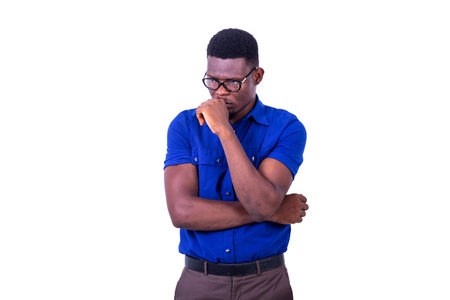 pensive young man wearing optical glasses, looking sideways with folded arm and raised hand on chin.