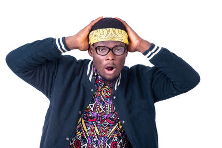 young man wearing yellow bandana and glasses, shocked with wide open mouth holding head with hands.の写真素材