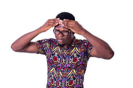 a handsome young man in glasses standing on white background feeling headache