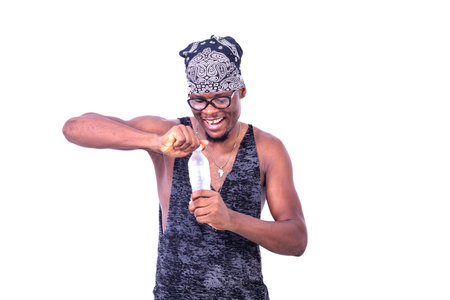 handsome happy young man wearing tank top and bandana on his head, opening a bottle of mineral water...