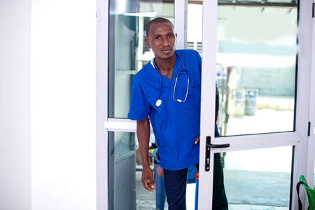 a doctor in uniform with a stethoscope opening the clinic door to enter itの写真素材