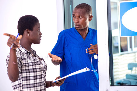 doctor in uniform with stethoscope standing discussing medical report with trainee in hospital