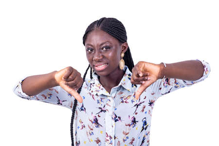 portrait of a beautiful displeased young woman pointing thumbs down while looking at the camera.の写真素材