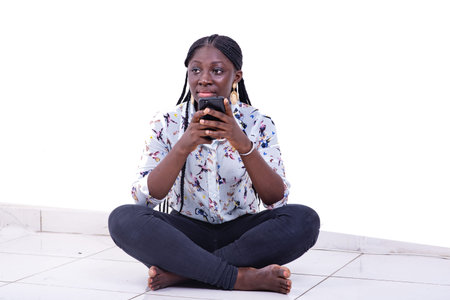 portrait of a beautiful young woman smiling chatting on mobile phone while sitting on the floor with...