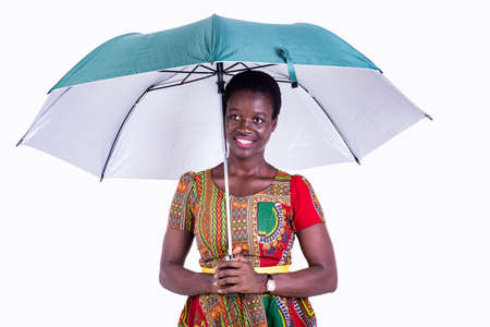 a beautiful young businesswoman in traditional dress standing on white background holding an umbrella and looking away smiling.の写真素材