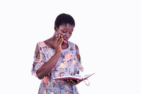 portrait of a beautiful young student woman surprised with wide open mouth while reading in her...