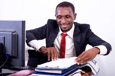 handsome adult businessman looking at document on clipboard in office while smiling.の写真素材