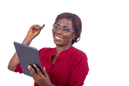 a beautiful businesswoman in glasses standing on a white background holding a tablet thinking and laughing.の写真素材