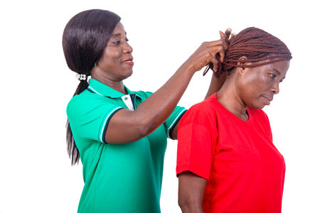 portrait of a beautiful woman in green t-shirt arranging hair of her comrade in red t-shirt while...